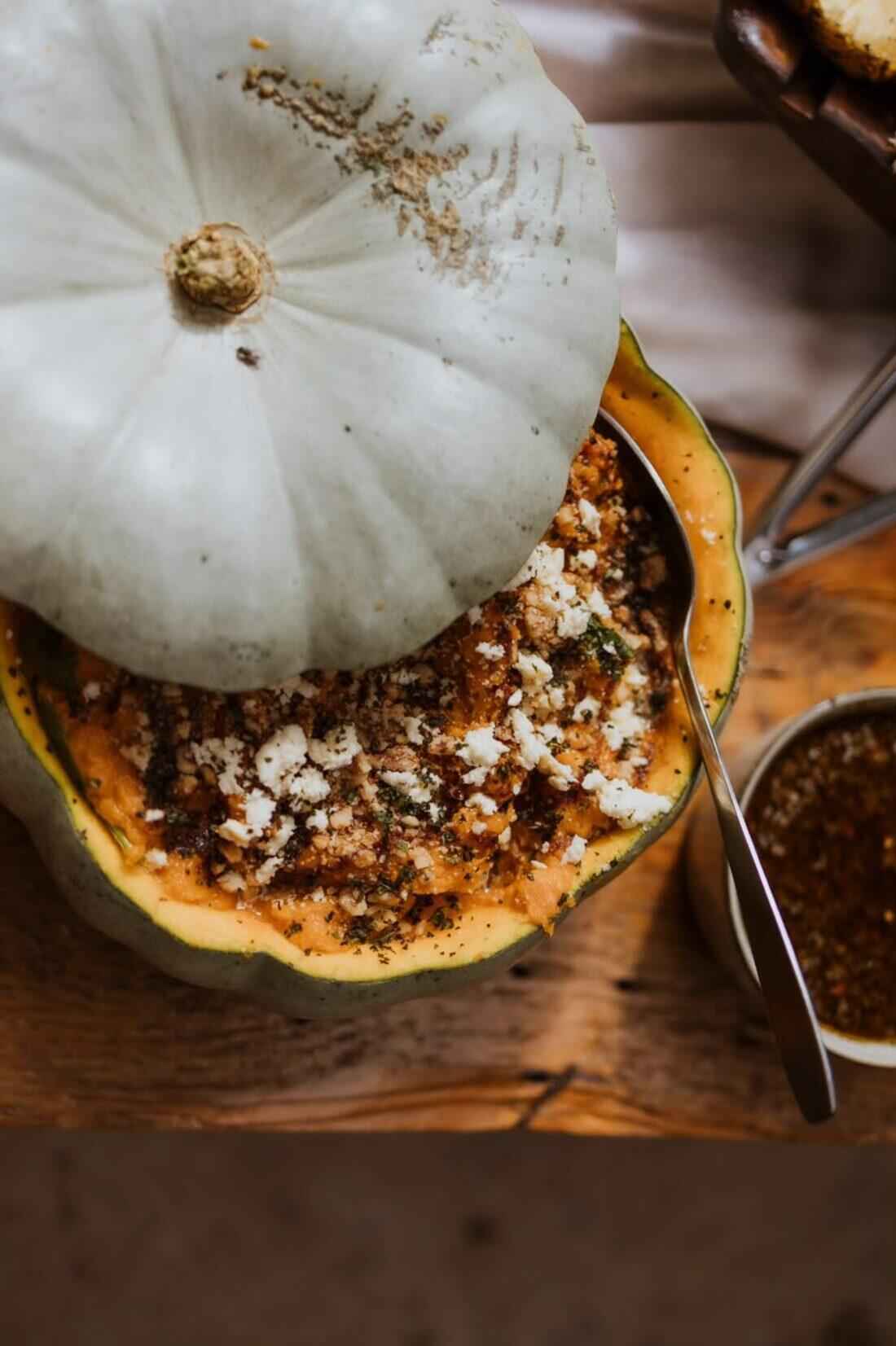 Whole fire-roasted pumpkin, charred and garnished with herbs and crumbled cheese