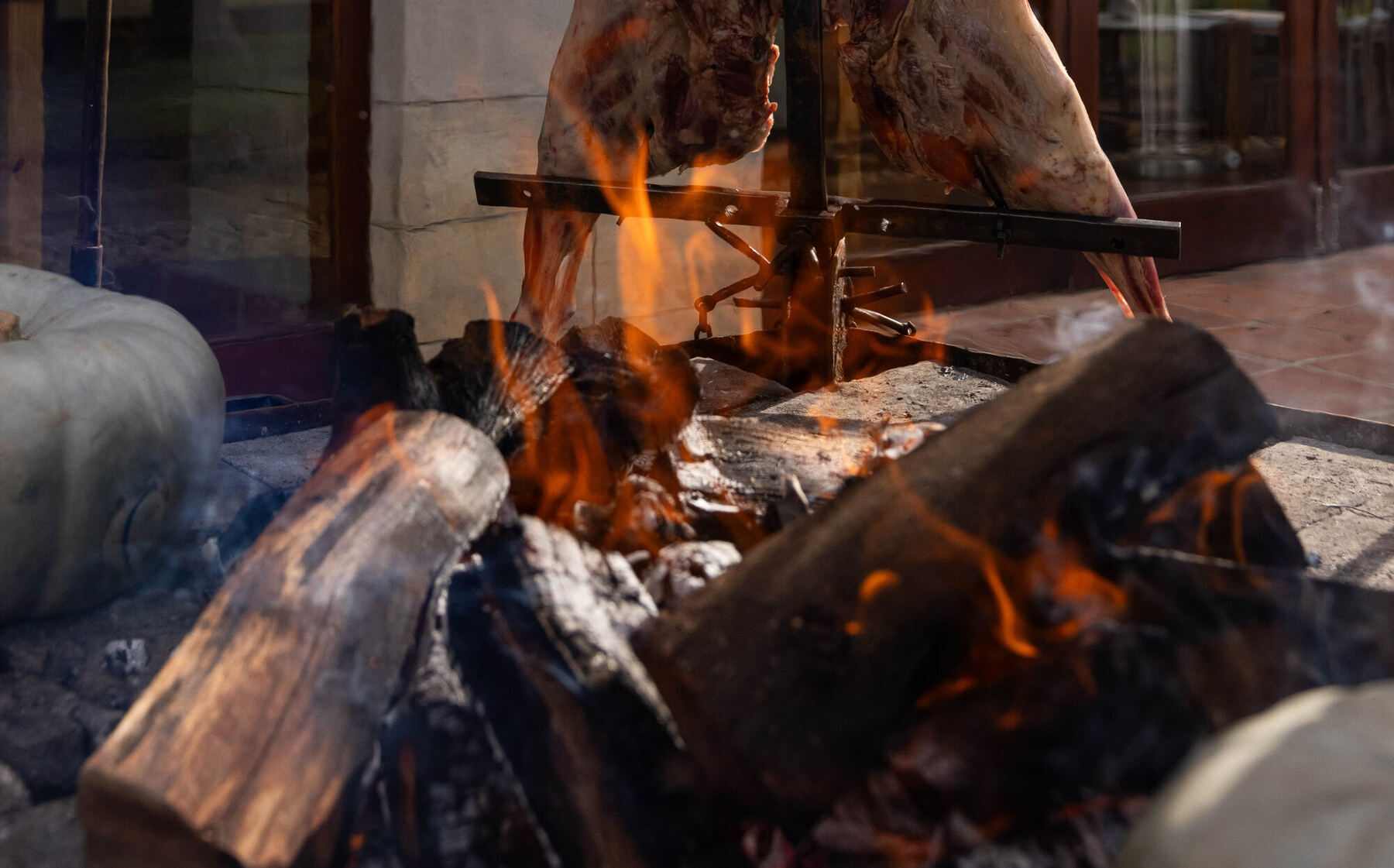 A whole lamb staked on the iron cross above an open fire
