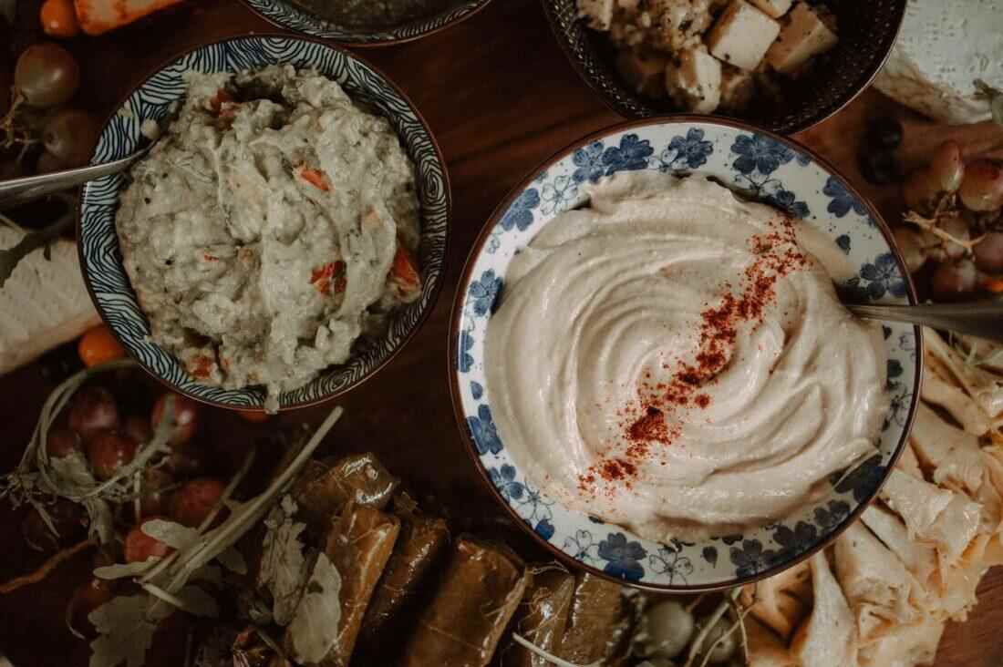 Fire-roasted dips with hummus and aubergine, surrounded by grapes and dolmades