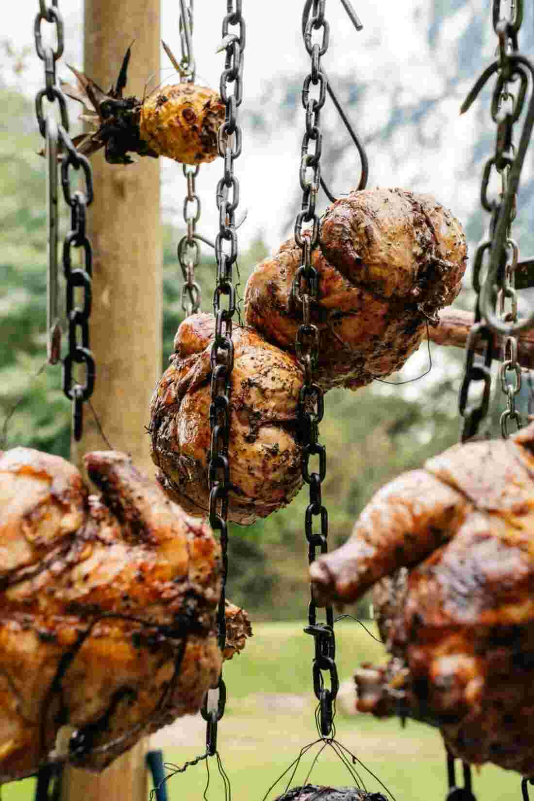 Roasted chickens hanging on chains over the fire